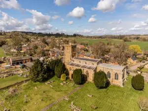 Aerial view of Saint Mary’s Church in Everdon, surrounded by village houses, farmland and rolling Northamptonshire countryside.