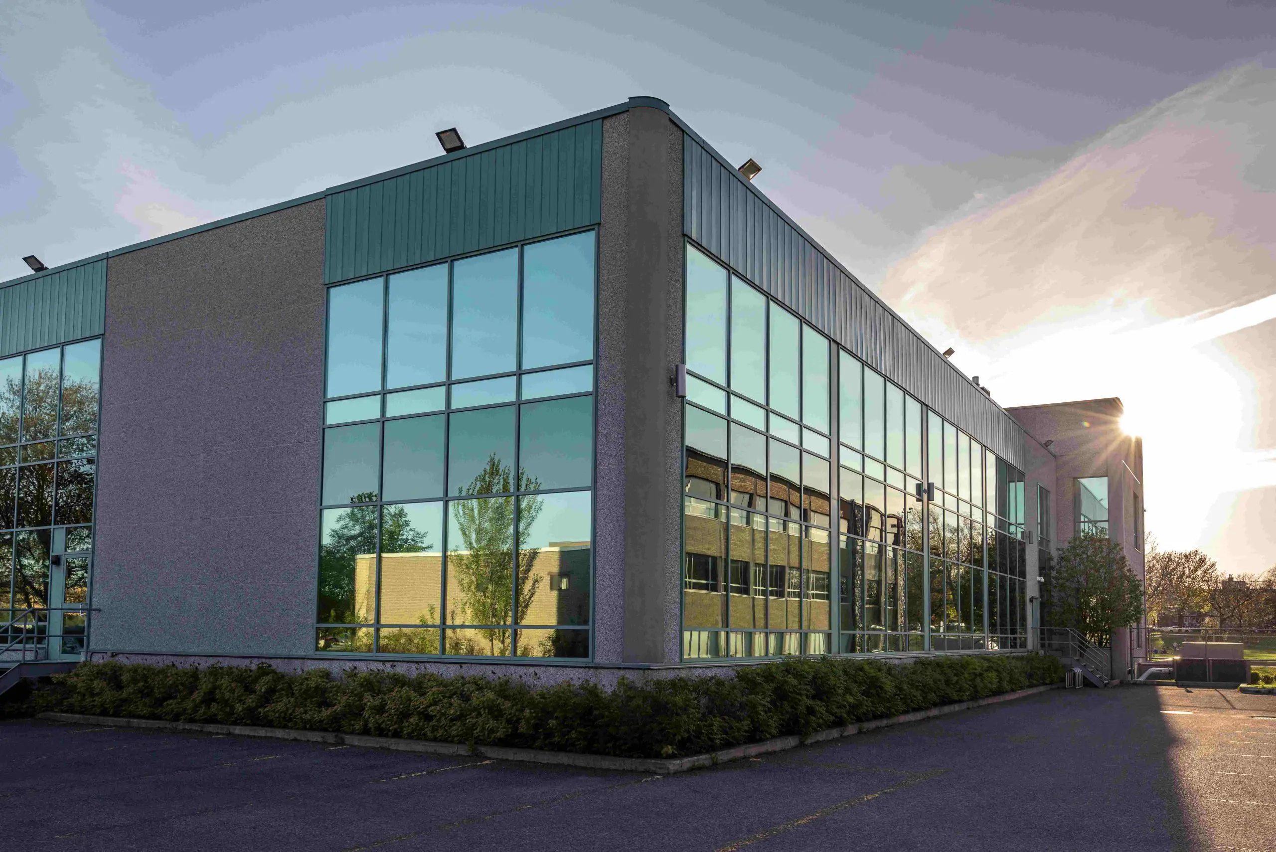 A modern commercial office building with extensive glazing and metal cladding, photographed at sunset, representing the type of property typically assessed during a pre-acquisition survey.