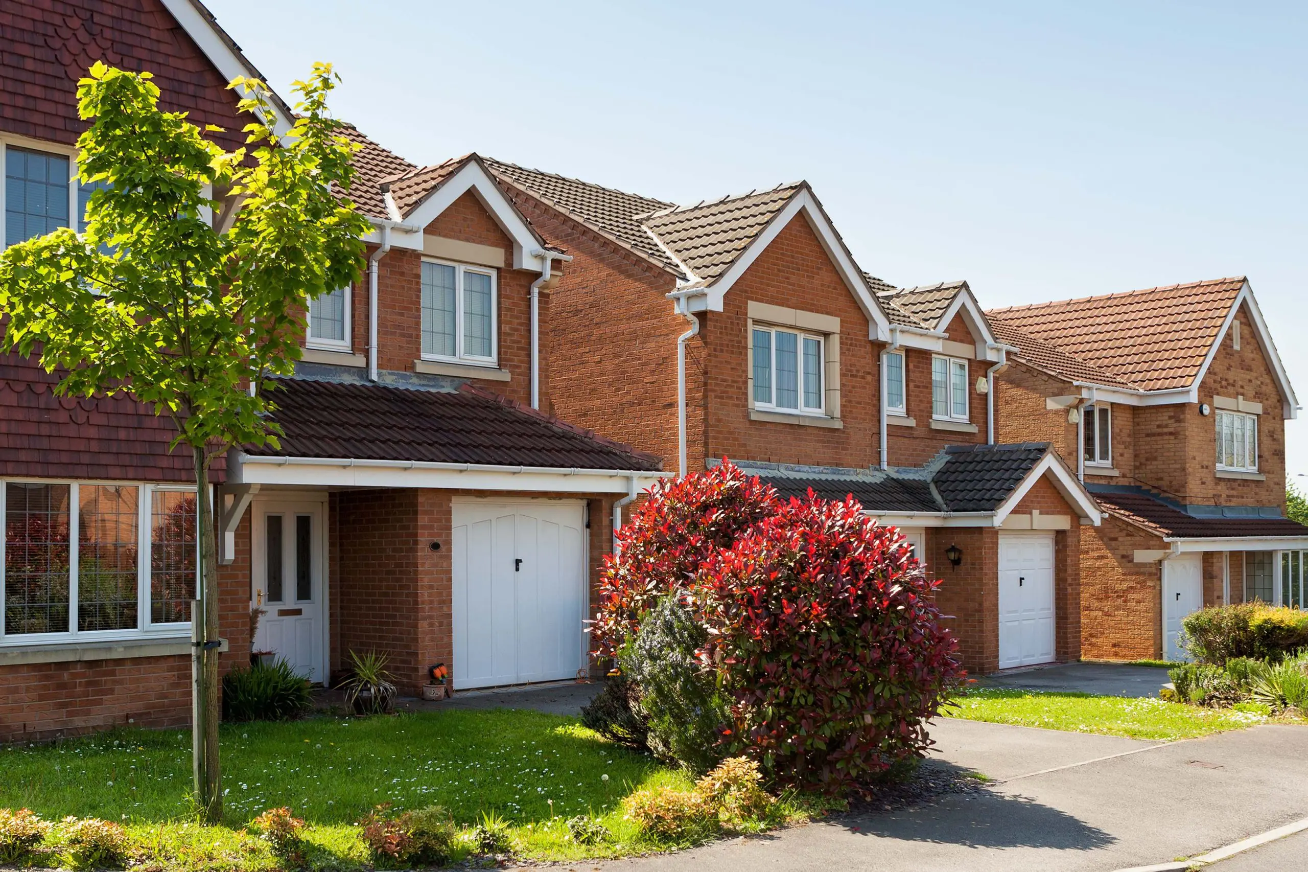 Modern British suburban houses with brick façades and tiled roofs, typical of properties assessed in RICS Home Survey Reports.