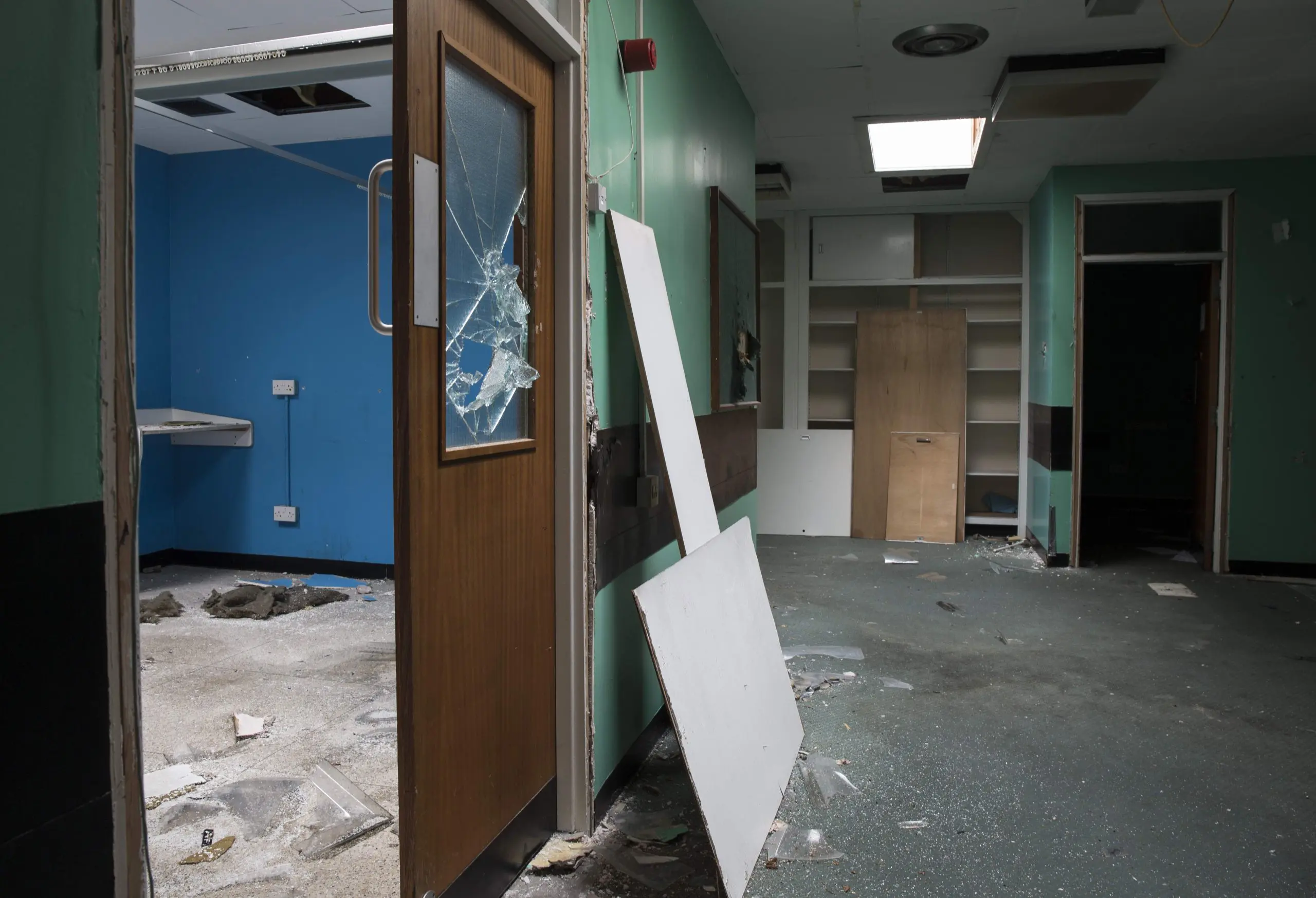Interior of a neglected commercial unit showing broken glazing, damaged partitions, missing ceiling panels and widespread disrepair, illustrating typical items recorded in a Schedule of Dilapidation.