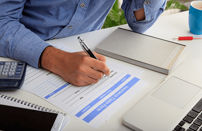 Insurance claim form with calculator and paperwork, illustrating the importance of accurate BCIS reinstatement valuations for buildings insurance.