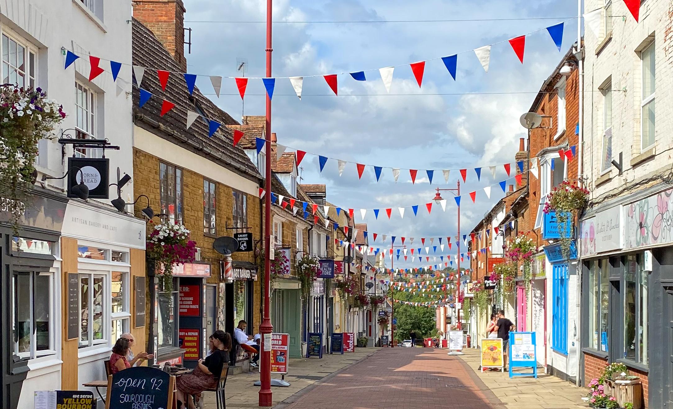 Sheaf Street, Daventry on a sunny day with bunting and outdoor cafe seating - rectangular image