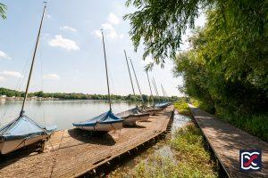 Sailing boats moored along the timber jetty at Drayton Reservoir in Daventry on a sunny day.