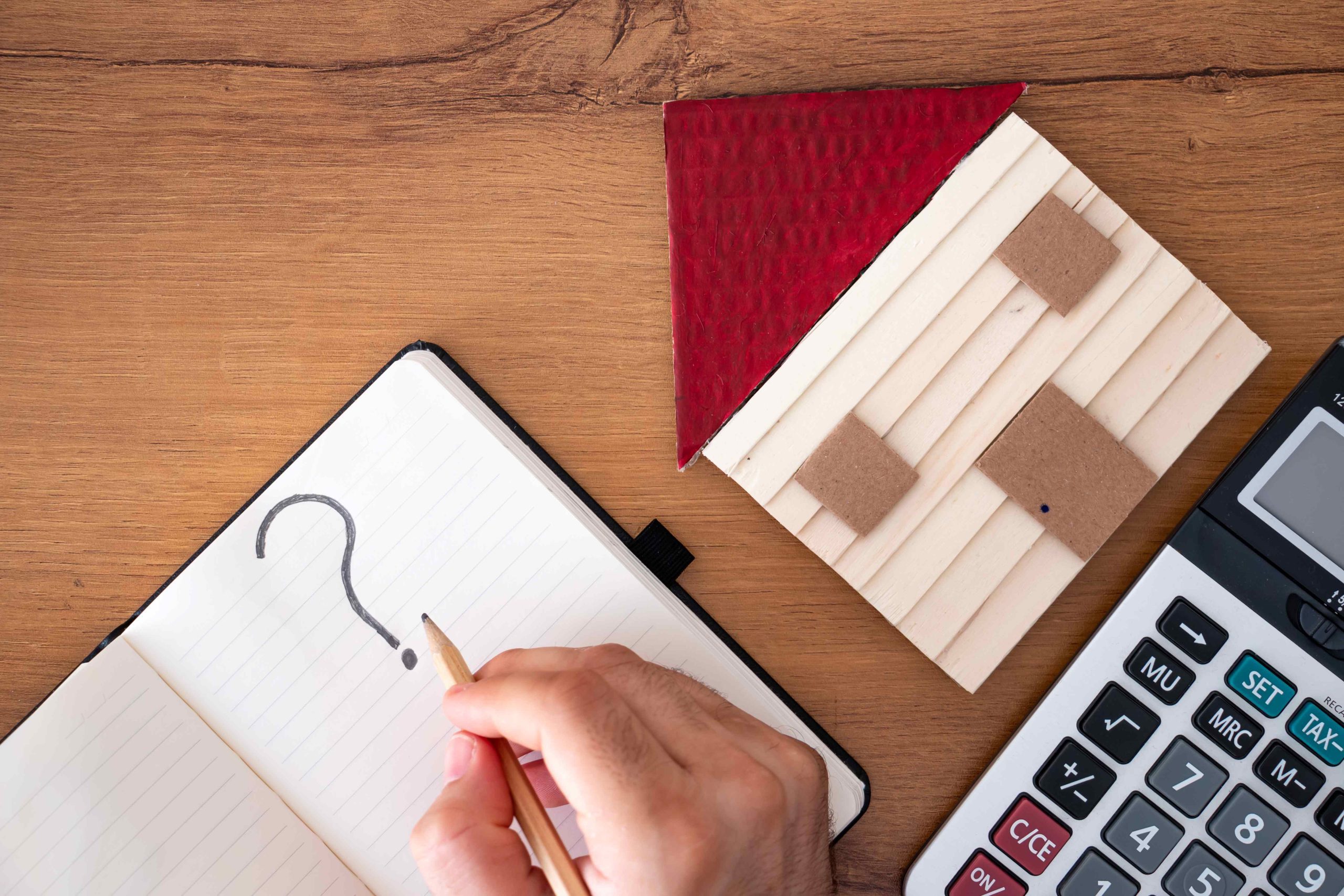 Notebook with question mark, calculator and model house symbolising residential property valuations including probate, Help-to-Buy, matrimonial and market valuations.